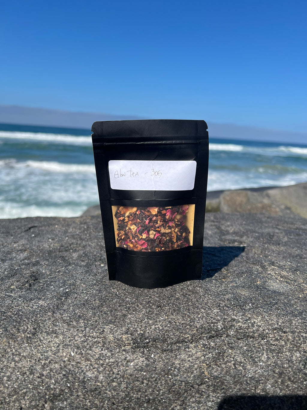 Onyx & Jade Tea Company Glow Tea pouch, featuring a caffeine free hibiscus and citrus blend with rosehips, honeybush, orange, lemon, rose, ginger, and lemongrass.