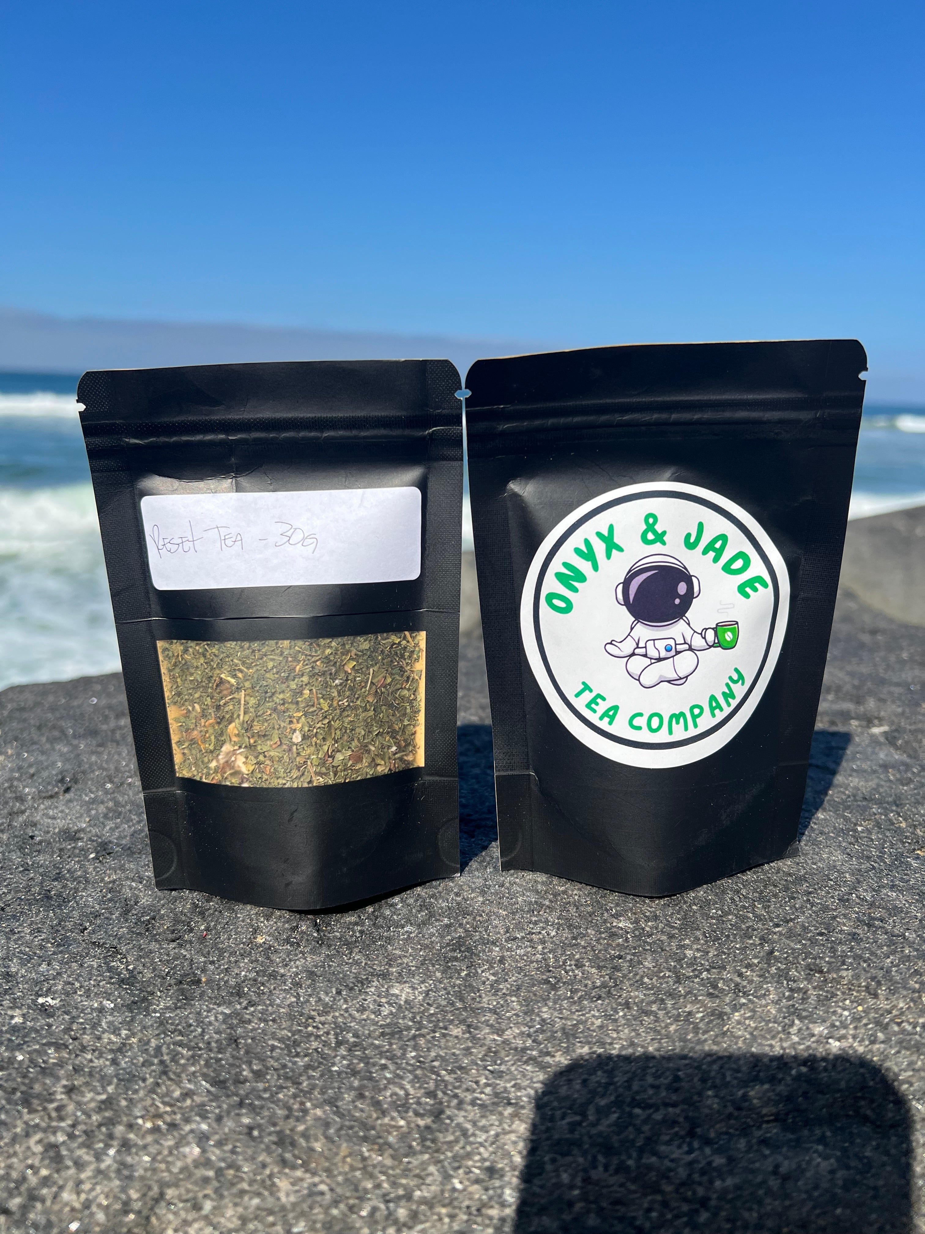 Front and back of the Onyx & Jade Tea Company Reset Tea package showing the product label, ingredients, simmering directions, caffeine information, and package details.